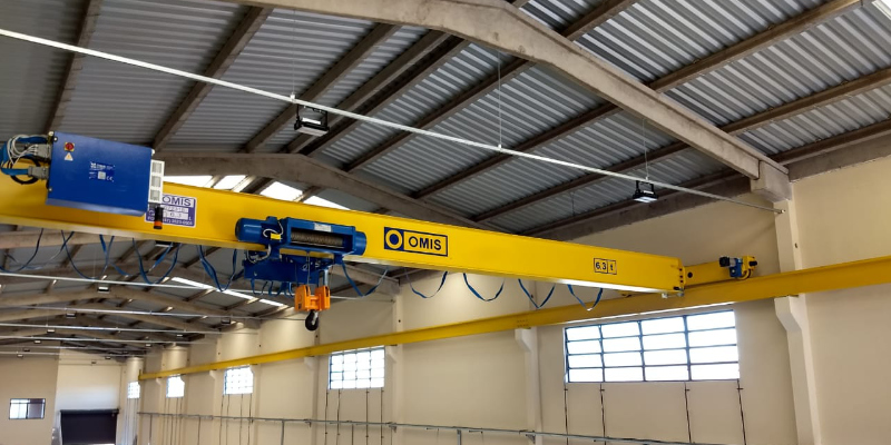 Ponte rolante monoviga amarela da OMIS instalada em um galpão industrial.